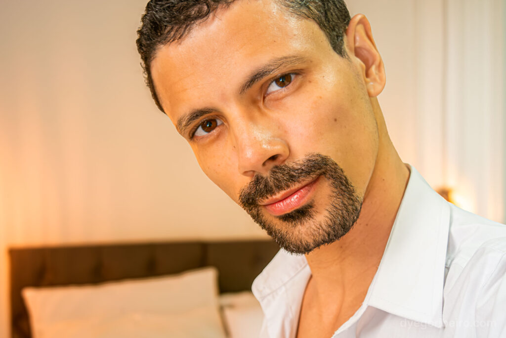 O fotógrafo Dyego Ribeiro em retrato aproximado (close-up) com camisa aberta, transmitindo proximidade e confiança em um ensaio lifestyle no RJ.